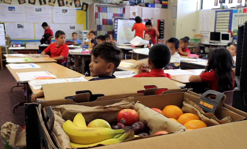 Students in a classroom with fresh fruit