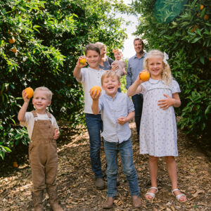 Family in the orange groves, kids holding fruit