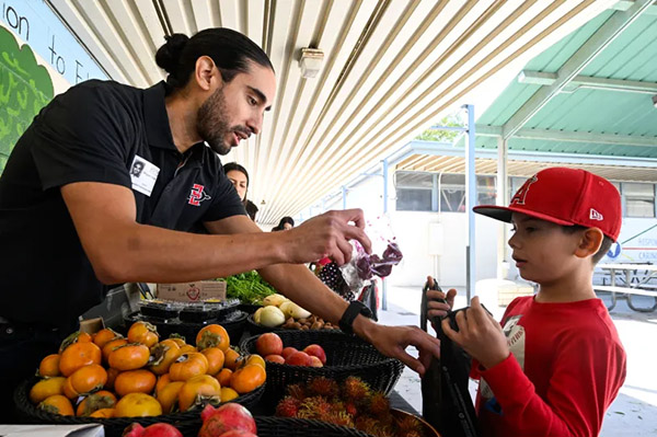 Man handing bag of sliced dragon fruit to small boy