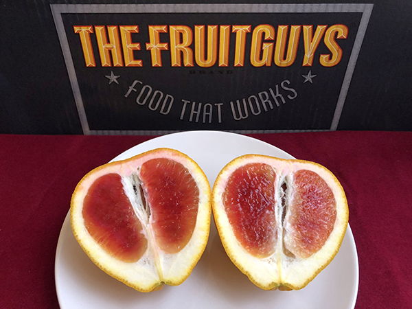 Valentine pomelo cut in half in front of a The FruitGuys Fruit that Works box