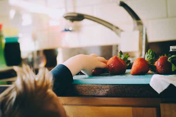 Kid grabbing strawberry off counter