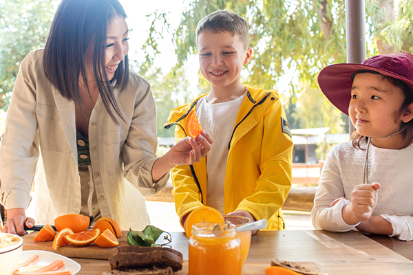 Smiling kids and teacher eating oranges